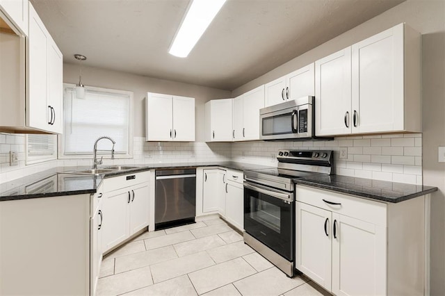 300 Yukon Ave, Yukon, OK 73099 - kitchen featuring appliances with stainless steel finishes, tasteful backsplash, white cabinets, light tile patterned floors, and dark stone counters