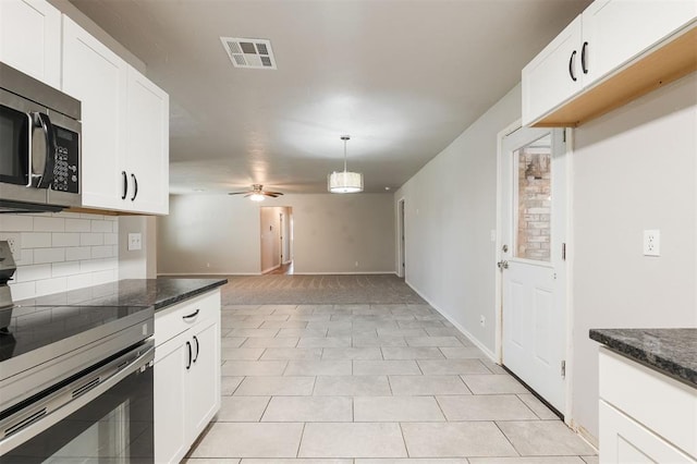 300 Yukon Ave, Yukon, OK 73099 - kitchen with stove, stainless steel microwave, backsplash, white cabinets, and a ceiling fan