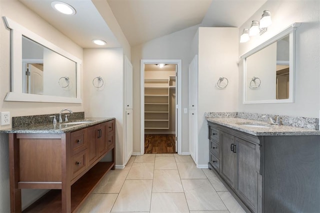 300 Yukon Ave, Yukon, OK 73099 - bathroom featuring two vanities, a spacious closet, vaulted ceiling, marble finish flooring, and recessed lighting