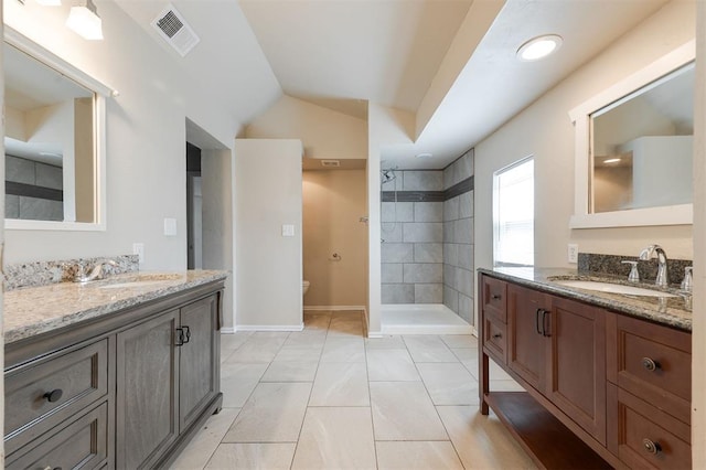 300 Yukon Ave, Yukon, OK 73099 - bathroom featuring two vanities, tiled shower, and lofted ceiling
