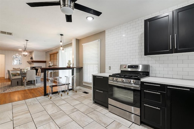 2800 Kerry Ln, Oklahoma City, OK 73120 - kitchen featuring stainless steel gas range, dark cabinets, light countertops, a ceiling fan, and backsplash