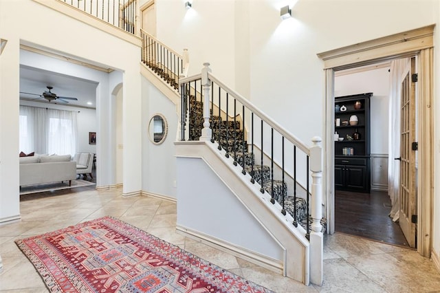 3101 White Cedar Dr, Moore, OK 73160 - stairway featuring arched walkways, a towering ceiling, tile patterned floors, and ceiling fan