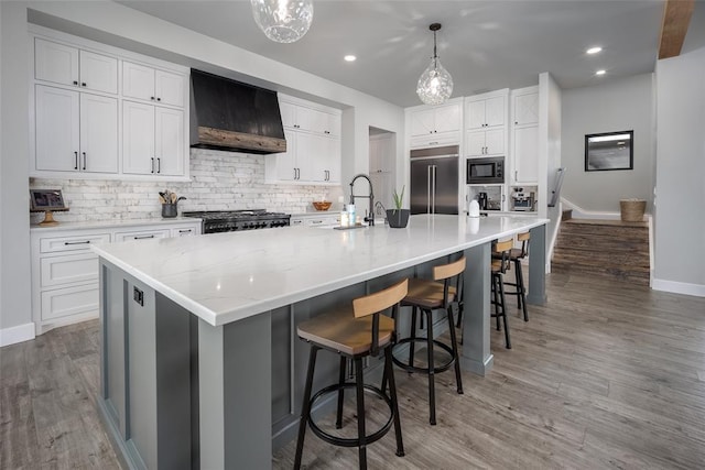 18569 310th St, Norman, OK 73072 - kitchen with premium range hood, built in appliances, light wood finished floors, tasteful backsplash, and a large island