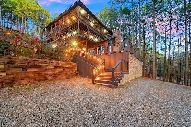 225 Stevens Rd, Broken Bow, OK 74728 - back of house with stairway, a balcony, stone siding, and a chimney