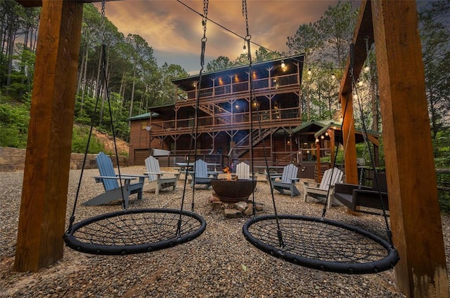 225 Stevens Rd, Broken Bow, OK 74728 - back of house at dusk with a fire pit, a wooden deck, and a patio