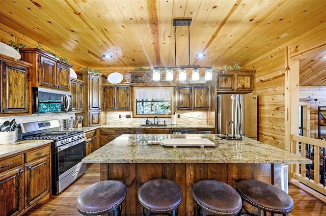 225 Stevens Rd, Broken Bow, OK 74728 - kitchen featuring stainless steel appliances, dark wood-style floors, a breakfast bar area, a kitchen island with sink, and backsplash