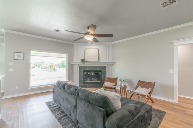 1848 County Road 1198, Tuttle, OK 73089 - living area featuring a tile fireplace, light wood finished floors, ceiling fan, and crown molding