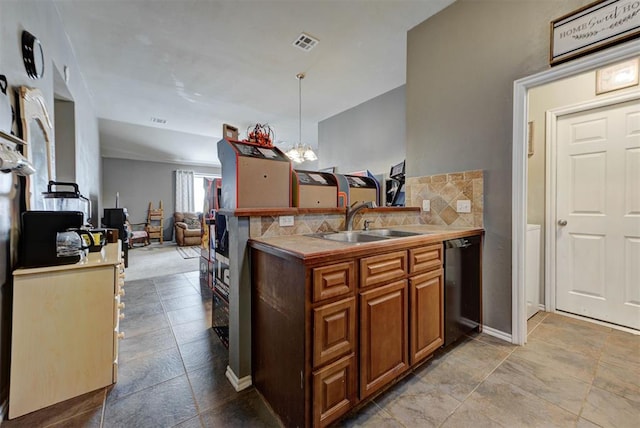 2233 NW 196th St, Edmond, OK 73012 - kitchen with black dishwasher, tasteful backsplash, a peninsula, hanging light fixtures, and brown cabinets