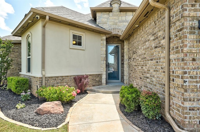 4600 Kentucky Ridge Dr, Mustang, OK 73064 - doorway to property featuring roof with shingles, brick siding, and stucco siding