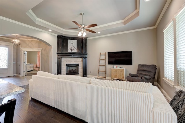 4600 Kentucky Ridge Dr, Mustang, OK 73064 - living room featuring a tray ceiling, healthy amount of natural light, arched walkways, a fireplace, and crown molding