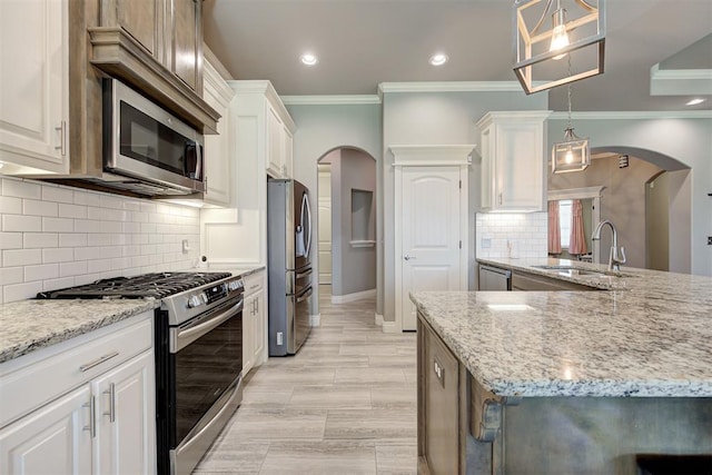 4600 Kentucky Ridge Dr, Mustang, OK 73064 - kitchen with stainless steel appliances, ornamental molding, arched walkways, light stone counters, and white cabinets
