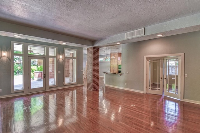 823 S Flood Ave, Norman, OK 73069 - unfurnished living room featuring a textured ceiling, wood finished floors, and healthy amount of natural light