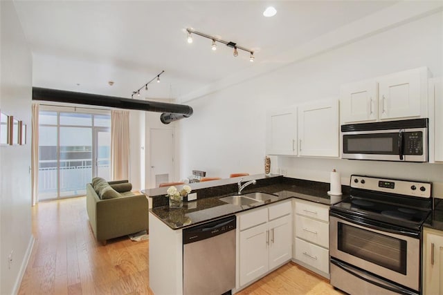 1 NE 2nd St Unit 402, Oklahoma City, OK 73104 - kitchen featuring stainless steel appliances, a peninsula, white cabinets, and dark stone countertops