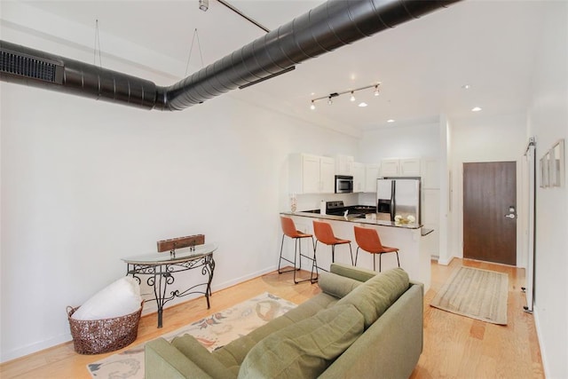 1 NE 2nd St Unit 402, Oklahoma City, OK 73104 - living room featuring a towering ceiling, light wood-style floors, and track lighting