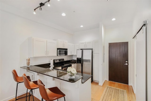 1 NE 2nd St Unit 402, Oklahoma City, OK 73104 - kitchen with appliances with stainless steel finishes, a peninsula, light wood finished floors, dark stone countertops, and a breakfast bar area