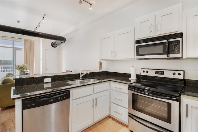 1 NE 2nd St Unit 402, Oklahoma City, OK 73104 - kitchen with stainless steel appliances, a peninsula, white cabinets, and dark stone countertops