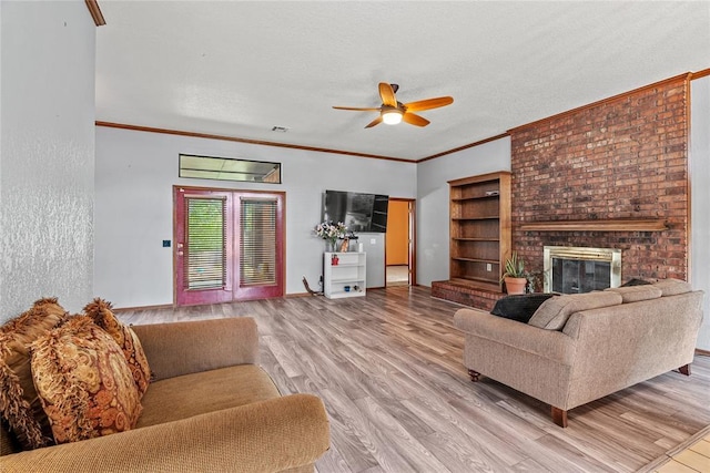 4924 Byron Cir, Yukon, OK 73099 - living room with ceiling fan, light wood finished floors, a fireplace, ornamental molding, and a textured ceiling