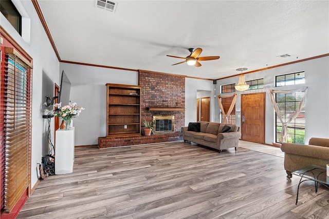 4924 Byron Cir, Yukon, OK 73099 - living area with crown molding, wood finished floors, ceiling fan, a fireplace, and a textured ceiling