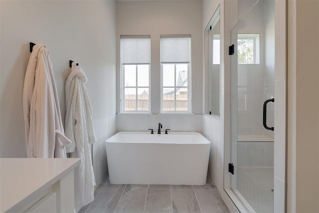 3624 Utica Square Dr, Edmond, OK 73034 - full bathroom featuring a freestanding tub, a stall shower, marble look tiles, vanity, and wainscoting