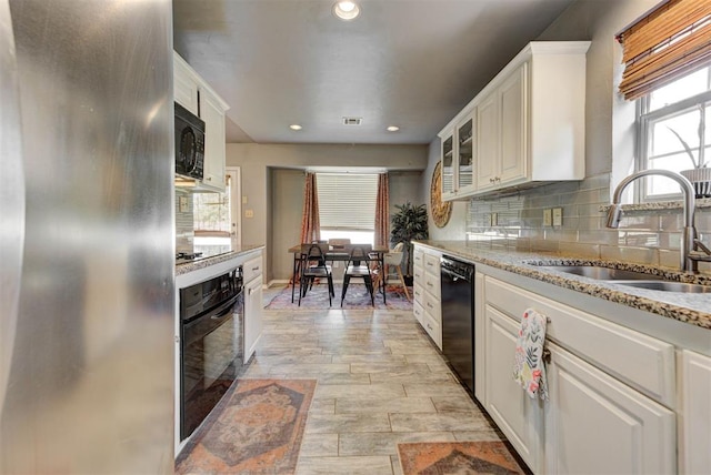1229 S Gemini Rd, Edmond, OK 73003 - kitchen with black appliances, white cabinets, light stone counters, backsplash, and recessed lighting