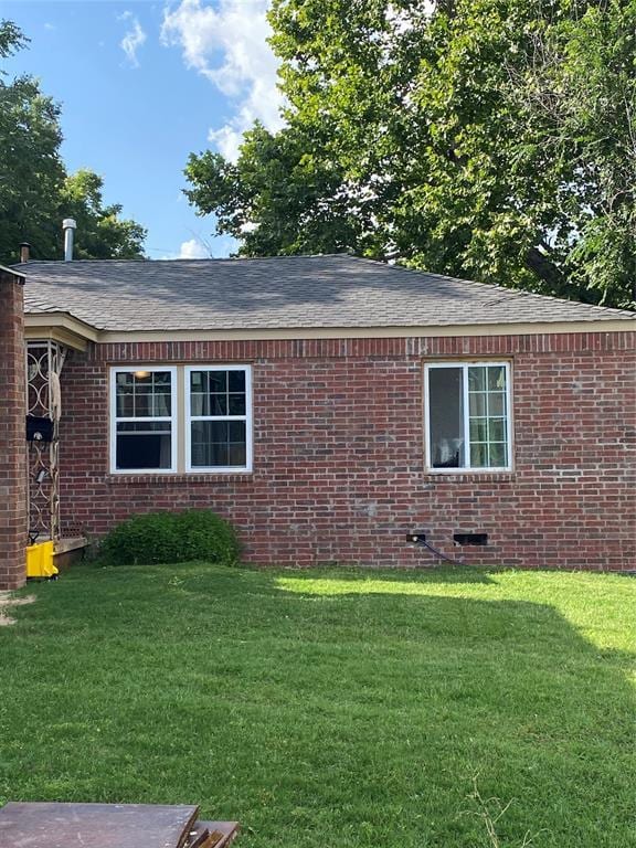 2451 NW 42nd St, Oklahoma City, OK 73112 - view of property exterior featuring a yard, brick siding, a shingled roof, and crawl space