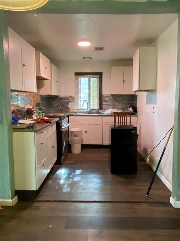 2451 NW 42nd St, Oklahoma City, OK 73112 - kitchen with stainless steel range, white cabinetry, decorative backsplash, dark wood-style floors, and dark countertops