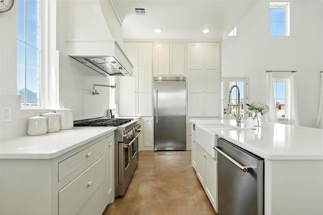 1006 Dorsi Way, Newcastle, OK 73065 - kitchen with high end appliances, premium range hood, concrete flooring, white cabinets, and light countertops