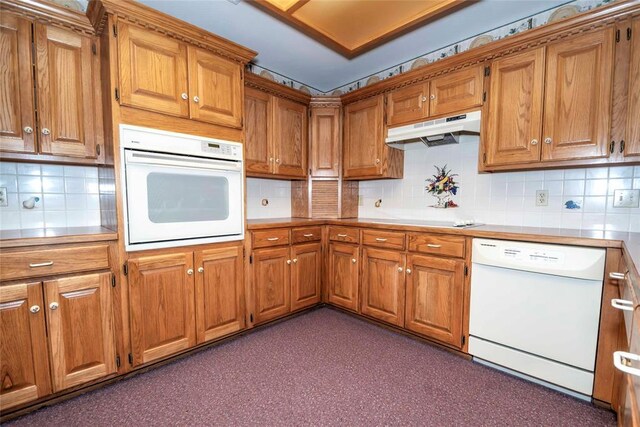 511 N Turner Rd, Chandler, OK 74834 - kitchen with white appliances, under cabinet range hood, brown cabinets, backsplash, and light countertops