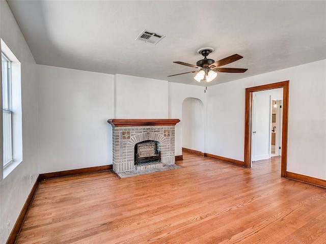 2212 N Kelham Ave, Oklahoma City, OK 73111 - unfurnished living room featuring wood finished floors, ceiling fan, arched walkways, and a fireplace