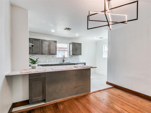 2212 N Kelham Ave, Oklahoma City, OK 73111 - kitchen featuring light countertops, a peninsula, decorative backsplash, light wood-type flooring, and ornamental molding