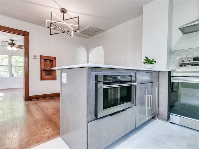 2212 N Kelham Ave, Oklahoma City, OK 73111 - kitchen with stainless steel appliances, range hood, light countertops, a chandelier, and ceiling fan