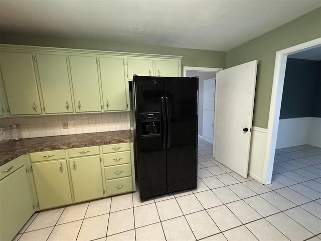 kitchen featuring black fridge, dark countertops, light tile patterned floors, and tasteful backsplash