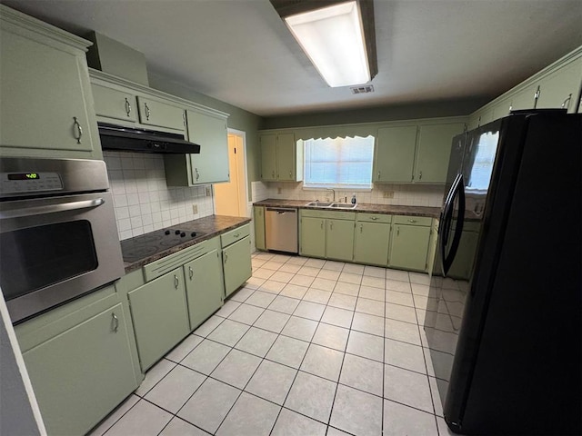 kitchen with black appliances, green cabinets, under cabinet range hood, and tasteful backsplash