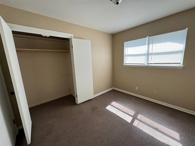 unfurnished bedroom featuring dark colored carpet and a closet