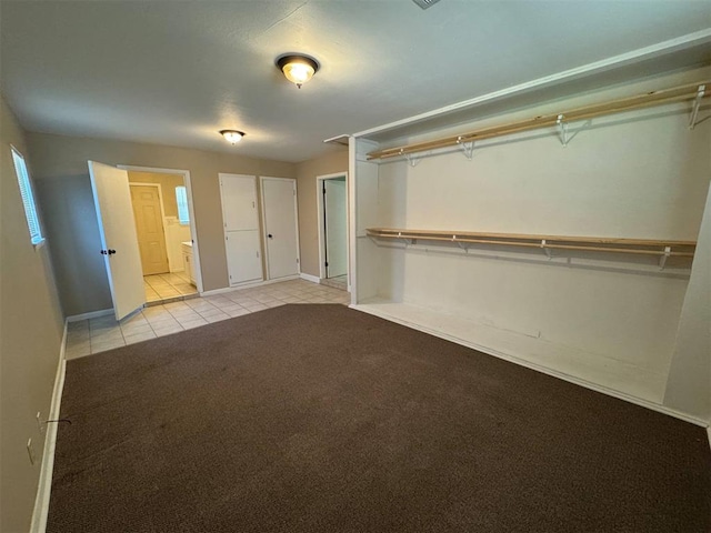 unfurnished bedroom featuring light tile patterned flooring, connected bathroom, and light colored carpet