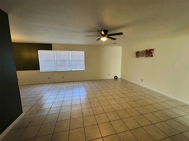 empty room featuring a ceiling fan, tile patterned flooring, and a textured ceiling