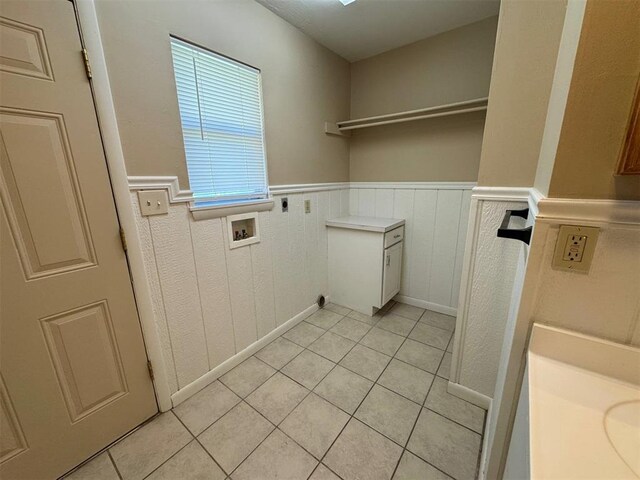 laundry room featuring electric dryer hookup, hookup for a washing machine, light tile patterned flooring, and wainscoting