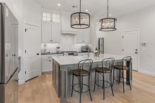 1724 Campus Corner Pl, Edmond, OK 73034 - kitchen with stainless steel appliances, light wood-type flooring, tasteful backsplash, a kitchen breakfast bar, and recessed lighting