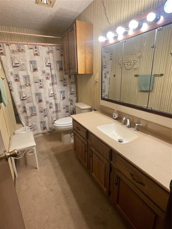 24400 Blackjack Rd, Perry, OK 73077 - full bathroom with vanity, wallpapered walls, a shower with curtain, and a textured ceiling
