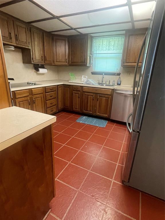 24400 Blackjack Rd, Perry, OK 73077 - kitchen featuring stainless steel appliances, dark tile patterned floors, light countertops, and brown cabinets