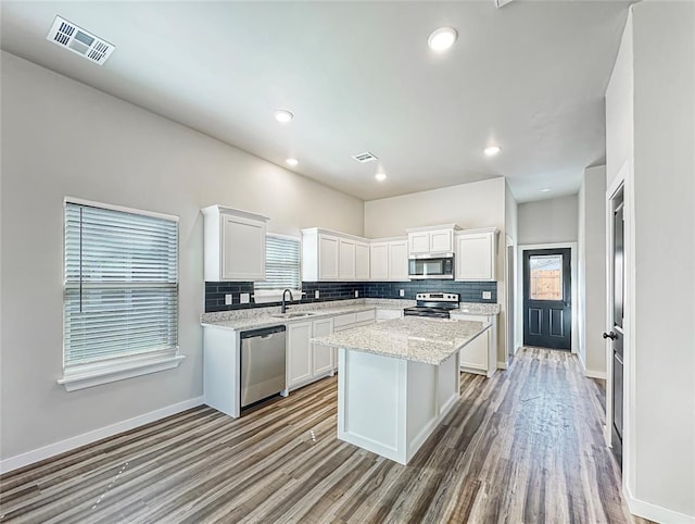 1101 N Tucker Ave, Shawnee, OK 74801 - kitchen featuring appliances with stainless steel finishes, tasteful backsplash, white cabinetry, wood finished floors, and recessed lighting