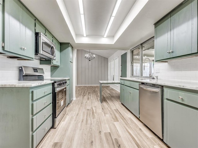 11516 N Barnes Ave, Oklahoma City, OK 73120 - kitchen with stainless steel appliances, green cabinets, light wood-style flooring, light countertops, and decorative backsplash