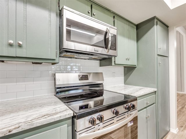 11516 N Barnes Ave, Oklahoma City, OK 73120 - kitchen with appliances with stainless steel finishes, green cabinets, light wood-style floors, and backsplash
