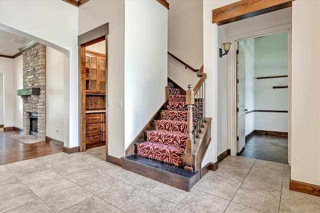 5000 Tower Bridge Court, Edmond, OK 73034 - staircase featuring crown molding, a stone fireplace, and tile patterned floors