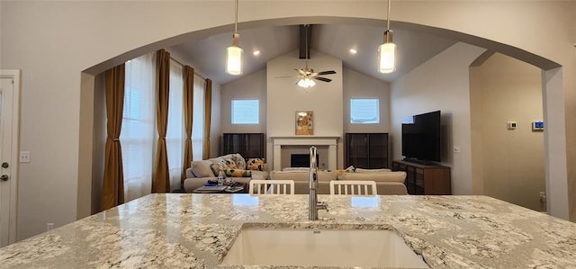 821 Mount Irving Way, Norman, OK 73071 - kitchen featuring arched walkways, light stone counters, a fireplace, and pendant lighting