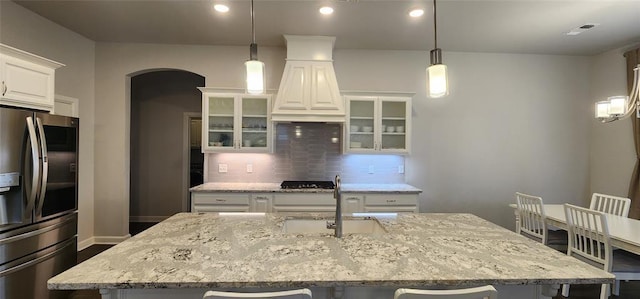 821 Mount Irving Way, Norman, OK 73071 - kitchen with appliances with stainless steel finishes, arched walkways, a kitchen bar, backsplash, and a kitchen island with sink