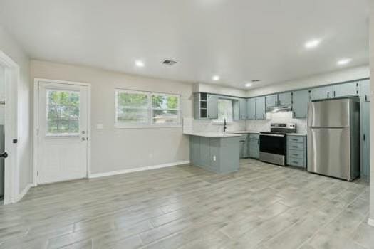 107 Cimarron Ter, Cashion, OK 73016 - kitchen with appliances with stainless steel finishes, light countertops, under cabinet range hood, light wood-style flooring, and recessed lighting
