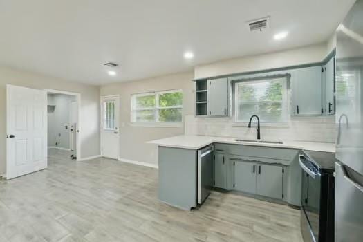 107 Cimarron Ter, Cashion, OK 73016 - kitchen featuring appliances with stainless steel finishes, a peninsula, backsplash, light countertops, and light wood finished floors