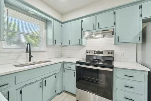 107 Cimarron Ter, Cashion, OK 73016 - kitchen with under cabinet range hood, stainless steel range with electric stovetop, tasteful backsplash, and light countertops
