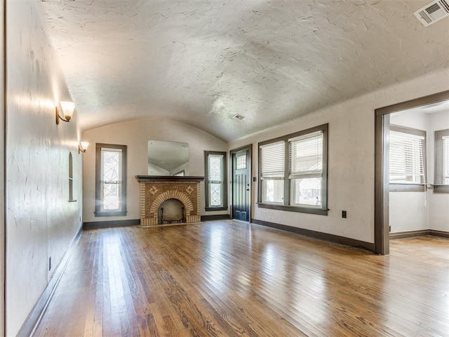 2420 NW 21st St, Oklahoma City, OK 73107 - unfurnished living room with hardwood / wood-style flooring, plenty of natural light, lofted ceiling, and a brick fireplace